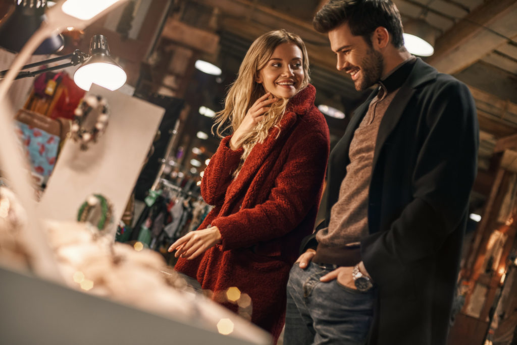 Happy young couple choosing handmade imitation jewelry at small street market